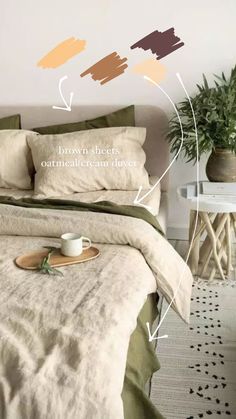 a bed with pillows and blankets on top of it next to a potted plant