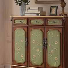 an ornate wooden cabinet with flowers painted on the doors and drawers is shown in this living room