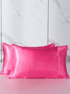 two pink satin pillows on a white table