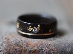 a close up of a wedding ring on top of a piece of wood with two diamonds