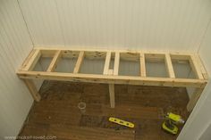 a wooden bench sitting on top of a hard wood floor next to a white wall