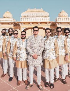 a group of men standing next to each other in front of a white and gold building