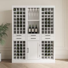 a white cabinet filled with lots of bottles and glasses next to a potted plant