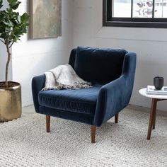 a living room with a blue velvet chair and potted plant