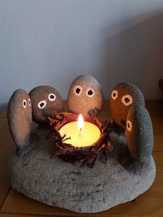 a lit candle surrounded by rocks with faces on them