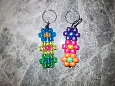 two keychains made out of beads on a marble surface, one is multicolored and the other is black