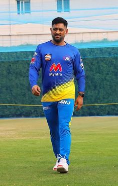 a man in blue and yellow uniform walking across a field with a soccer ball on the ground