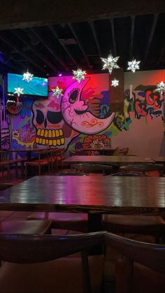 an empty restaurant with tables and chairs in front of colorful wall paintings on the walls