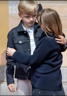 two young children are hugging each other in front of a building with steps behind them