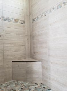 a bathroom with a tiled shower and wooden flooring on the walls, along with a bench in the corner