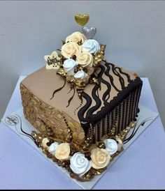 the cake is decorated with gold and white flowers on it's side, along with two hearts