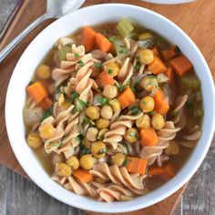 a white bowl filled with pasta and veggies next to a wooden cutting board