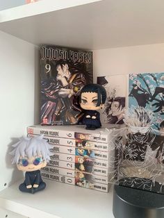 two anime figurines sitting on top of a shelf next to posters and books