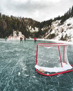 people playing ice hockey on an icy lake with mountains in the backgrouds