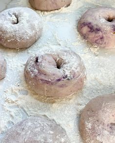 doughnuts are covered in powdered sugar on a baking sheet, ready to be baked