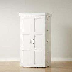 a tall white cabinet sitting on top of a hard wood floor