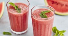 two glasses filled with watermelon smoothie next to slices of watermelon