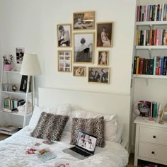 a laptop computer sitting on top of a bed in a room with bookshelves