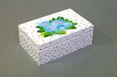 a white box with a blue flower painted on the side and polka dots around it