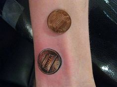 a person with a small tattoo on their wrist has a penny in front of them