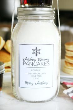 a glass jar filled with cake mix sitting on top of a counter next to pancakes