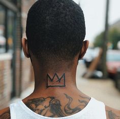 the back of a man's head with a crown tattoo on his left neck