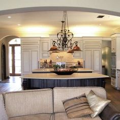 a large open concept kitchen and living room with an archway leading to the dining area