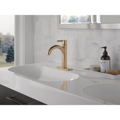 a bathroom sink with a gold faucet and soap dispenser next to it