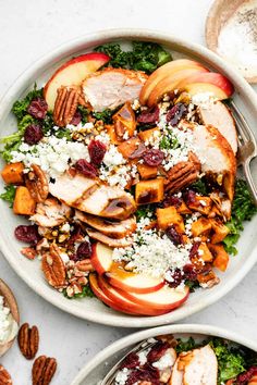 two bowls filled with salad topped with apples and pecans