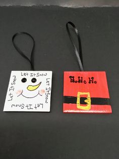 two handmade christmas tags sitting on top of a black table next to each other