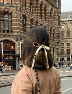 a woman walking down the street in front of a building with a bow on it's back