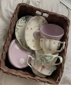 a wicker basket filled with dishes and cups