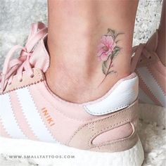 a close up of a person's foot with a flower tattoo on the ankle