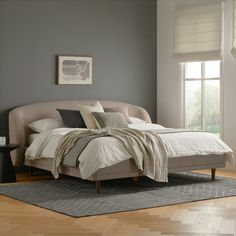 a bed sitting on top of a wooden floor next to a window