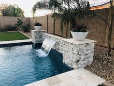 a small pool with a waterfall in the middle and plants on it's side