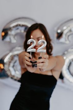 a woman in a black dress holding two candles with the number 22 on it,