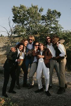 a group of people standing next to each other in front of trees and dirt ground