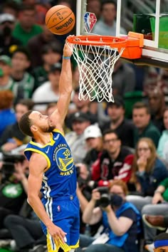 a basketball player dunking the ball into the hoop during a game with fans watching