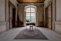 an empty room with a table and chair in the middle, surrounded by large windows