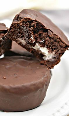 two chocolate desserts on a white plate with one cut in half and the other partially eaten