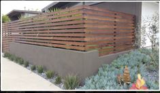 a modern house with wood slats on the side and plants growing in the front yard