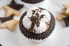 chocolate cupcakes with white frosting and star shaped cookies on the side, sitting on a plate