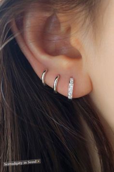 a close up of a person's ear with two small silver hoops on it