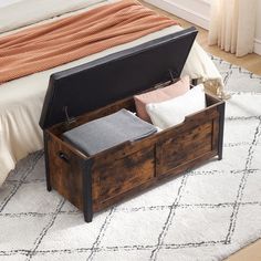 an open trunk sitting on top of a bed next to a white rug in a bedroom