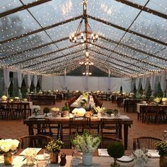 a large tent with tables and chairs set up for an event or wedding reception in the evening