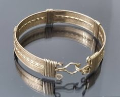 An very unusual 9ct rolled gold wire bangle. It consists of gold wire strands that are wound around the bangle at intervals and also finishing off each end. Hook and eye clasp are also made from these rolled gold sturdy wires. Dates from around 1910-1930. Good condition, wear to the rolled gold is present but commensurate with age. Width is 10mm Diametr is 5.4cm Gold Metal Wire Wrapped Bangle, Gold Wire Wrapped Metal Bangle, Wire Wrapped Gold Metal Bangle, Bronze Wire Wrapped Bangle Bracelet, Artisan Gold Cuff Bangle Bracelet, Artisan Gold Bangle Cuff Bracelet, Artisan Gold Cuff Bracelet Hand Wrapped, Yellow Gold Wire Wrapped Bangle, Artisan Gold Round Bracelets