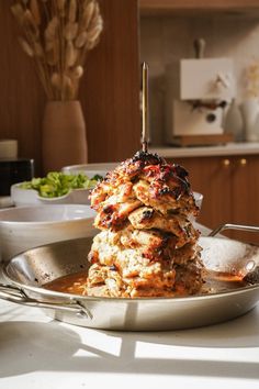 a stack of pancakes sitting on top of a pan filled with syrup and meat covered in sauce