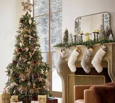 a decorated christmas tree in front of a fireplace with stockings hanging from the mantel