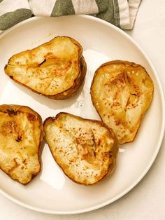 four pieces of baked potatoes on a white plate next to a green and white napkin