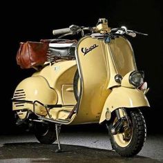 a yellow scooter parked in front of a black background with a brown leather bag on the seat